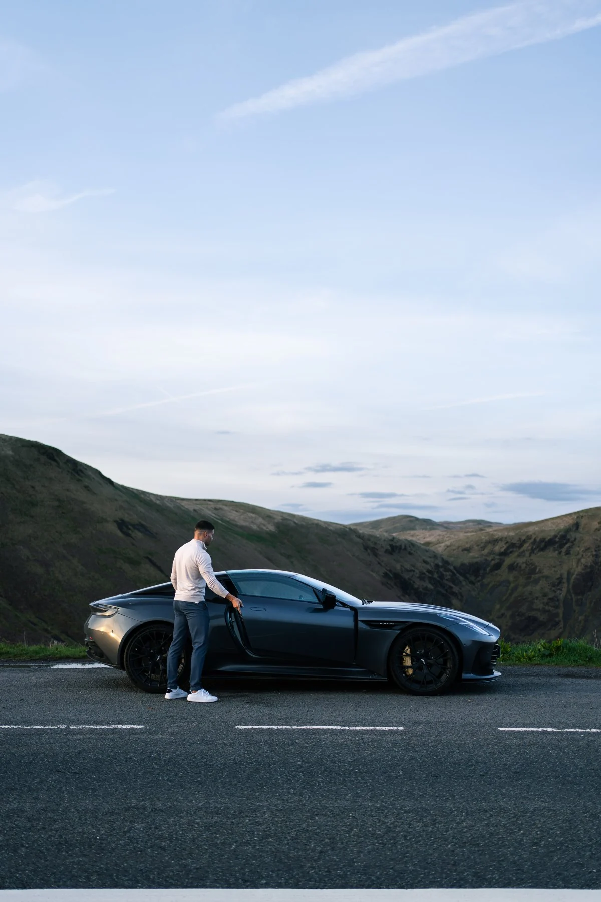 Murray Clark beside an Aston Martin on a mountain road