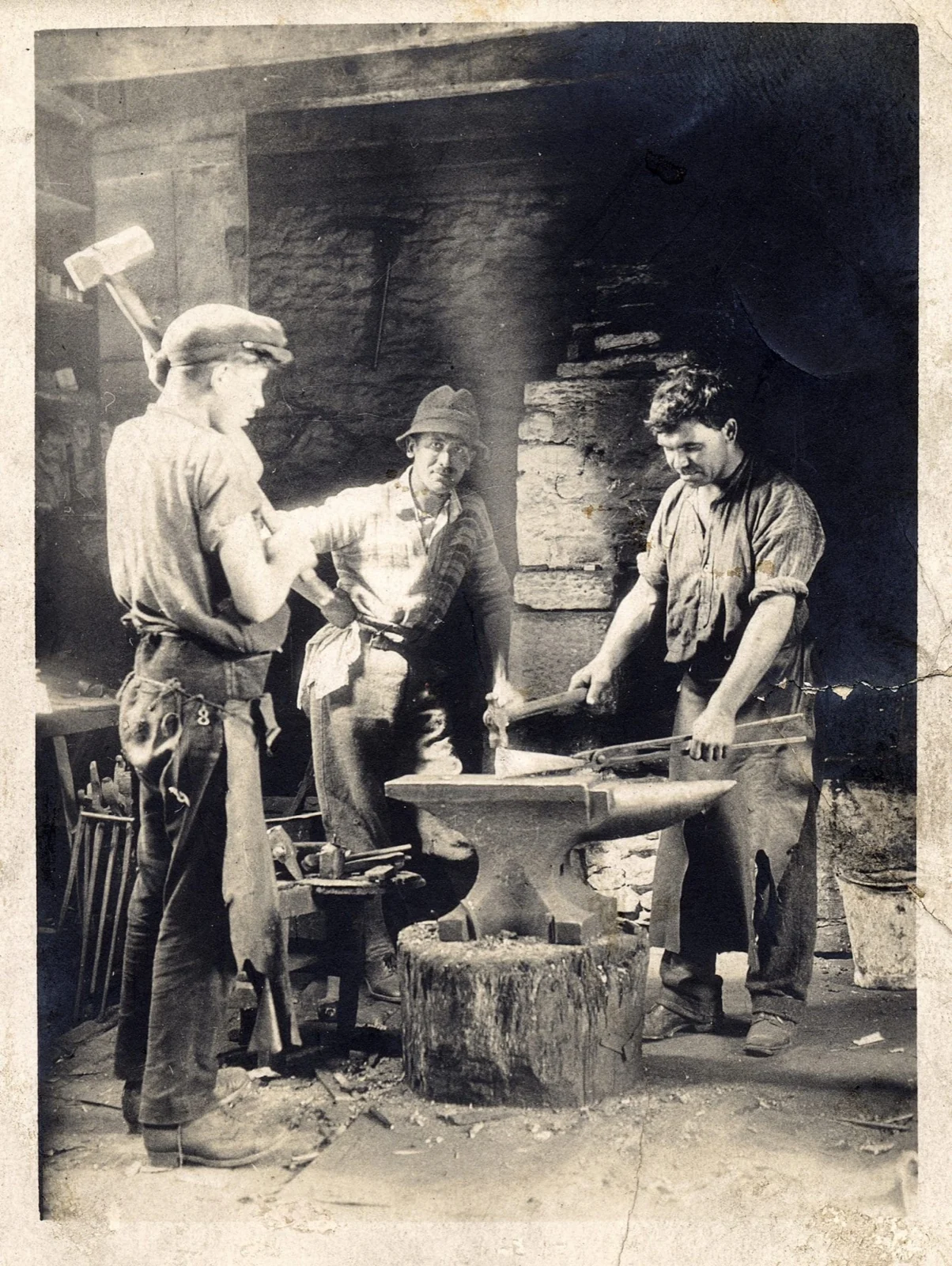 Archive photograph of blacksmiths gathered around an anvil