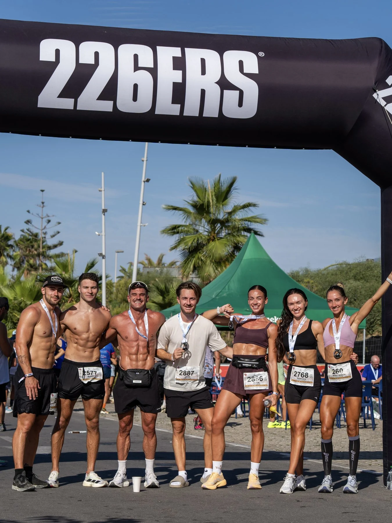 Friends gathered together beneath a race finish arch