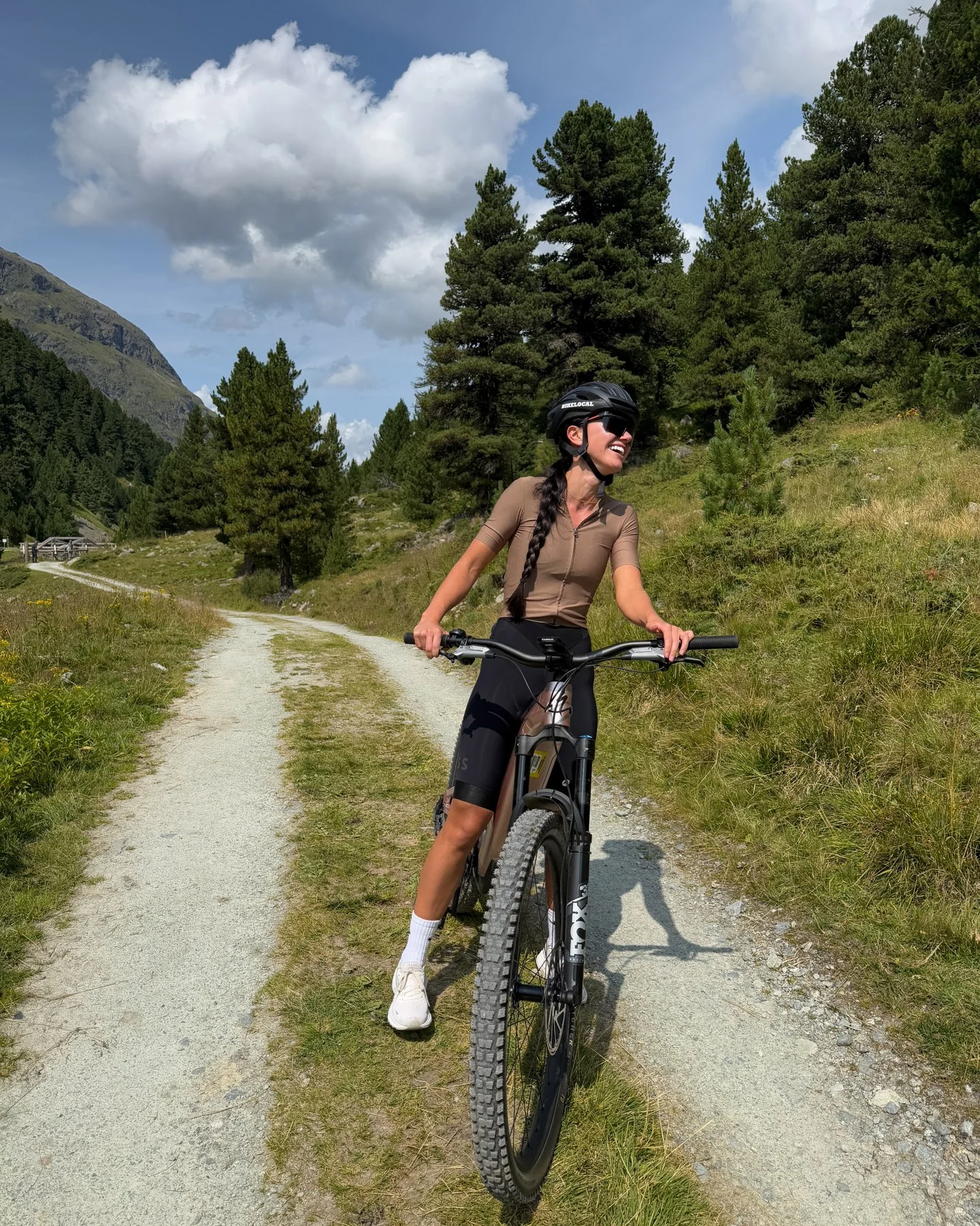 A mountain biker on a gravel trail beneath alpine peaks
