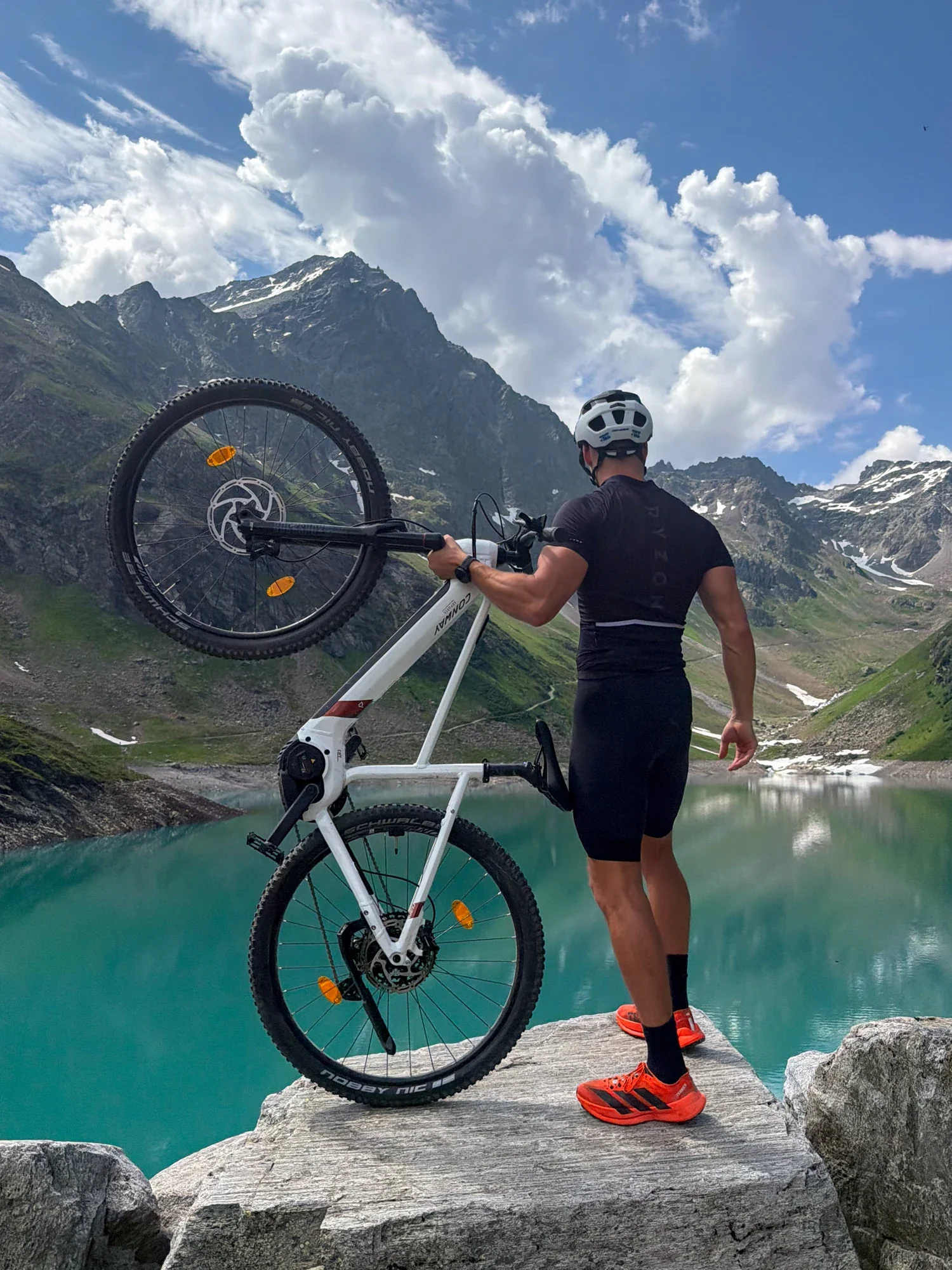 Murray Clark holding his bike beside an alpine lake