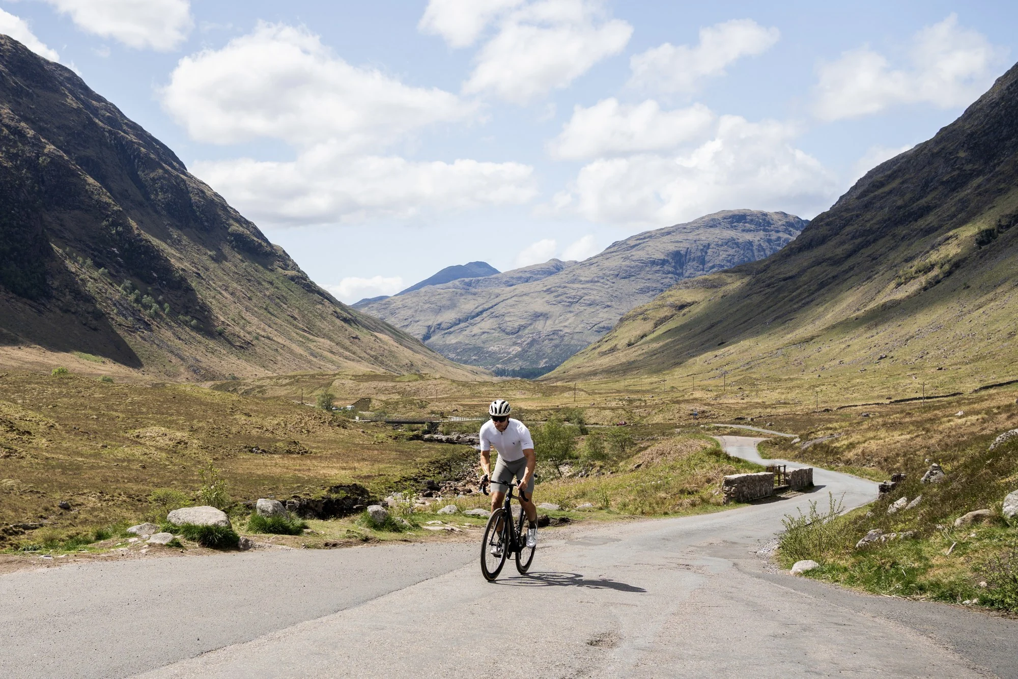 Murray Clark cycling along a winding road through a mountain valley