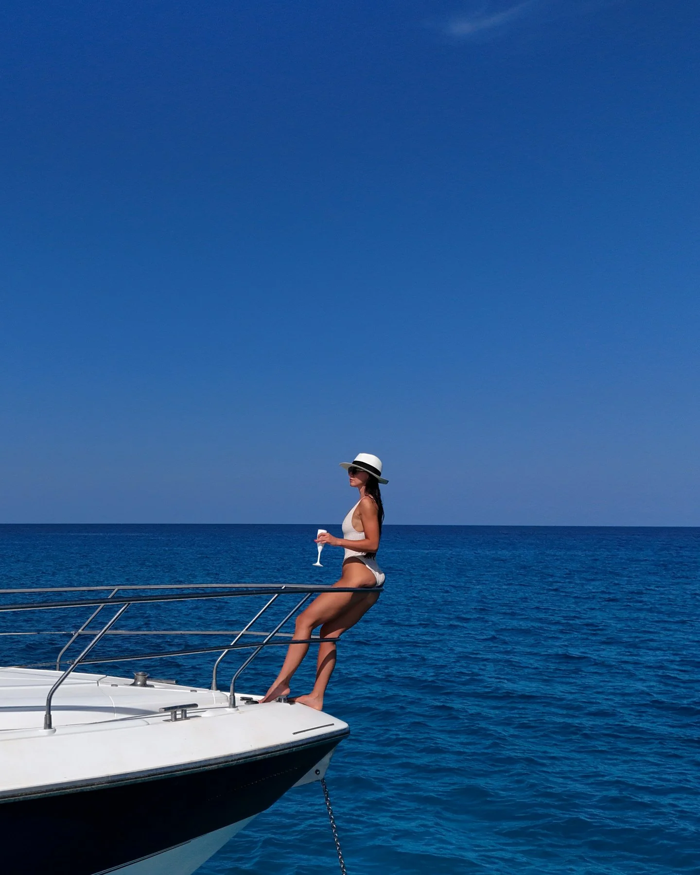 Rebecca sitting on the bow of a yacht above the blue sea